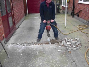 Digging up the driveway using a jack hammer.